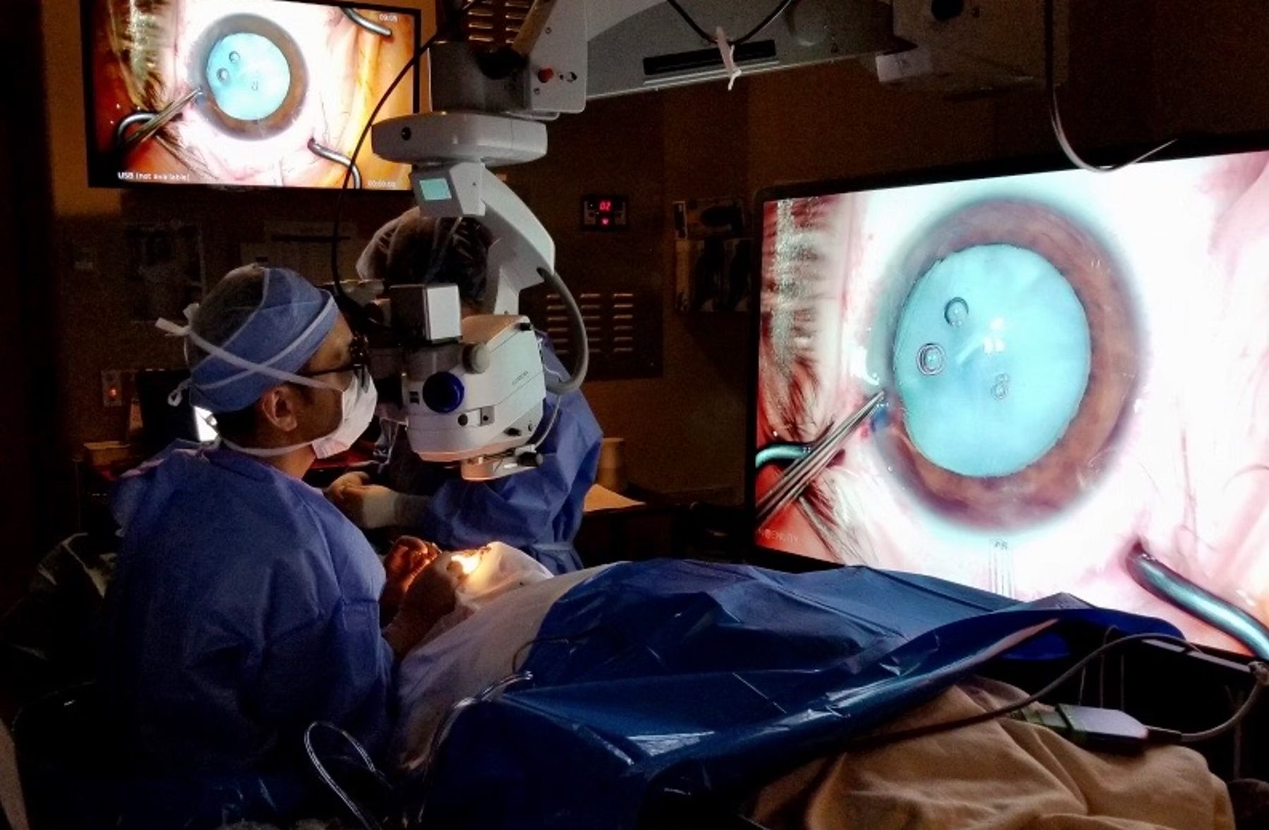 Cataract surgery in progress at the Hamilton Regional Eye Institute, with microscope-guided view displayed on screen